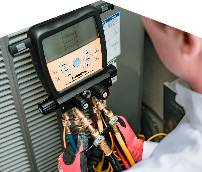 A Haven Home service crew member uses a digital manifold gauge to check refrigerant levels on an HVAC unit for service. A Haven Home service crew member uses a digital manifold gauge to check refrigerant levels on an HVAC unit for service.