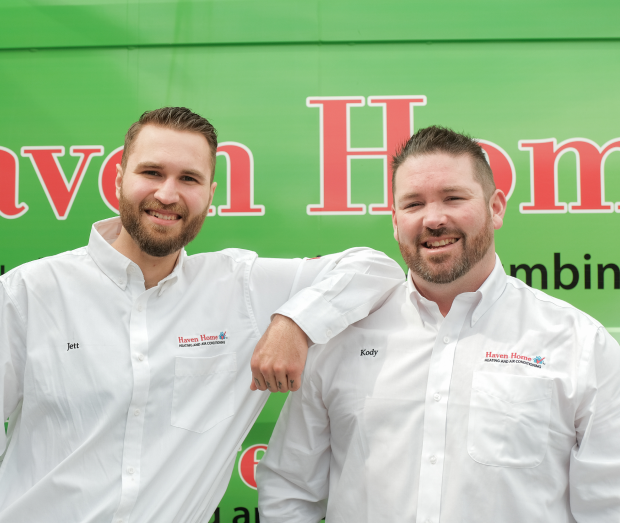 Smiling Haven Home technician standing confidently in front of their green service van, wearing their white issued uniform. Smiling Haven Home technician standing confidently in front of their green service van, wearing their white issued uniform.