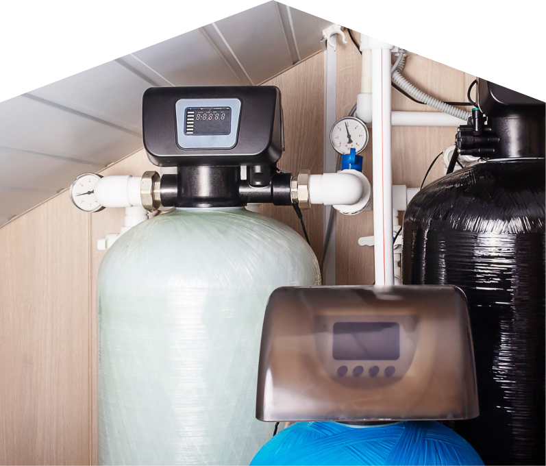 Haven Home home water filtration system featuring resin tanks, digital control heads, pressure gauges, and connected piping in a utility room. Haven Home home water filtration system featuring resin tanks, digital control heads, pressure gauges, and connected piping in a utility room.