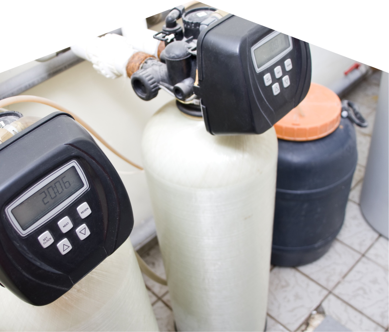 Haven Home water softener installation showing dual resin tanks with digital control heads and a brine tank in a tiled utility area. Haven Home water softener installation showing dual resin tanks with digital control heads and a brine tank in a tiled utility area.